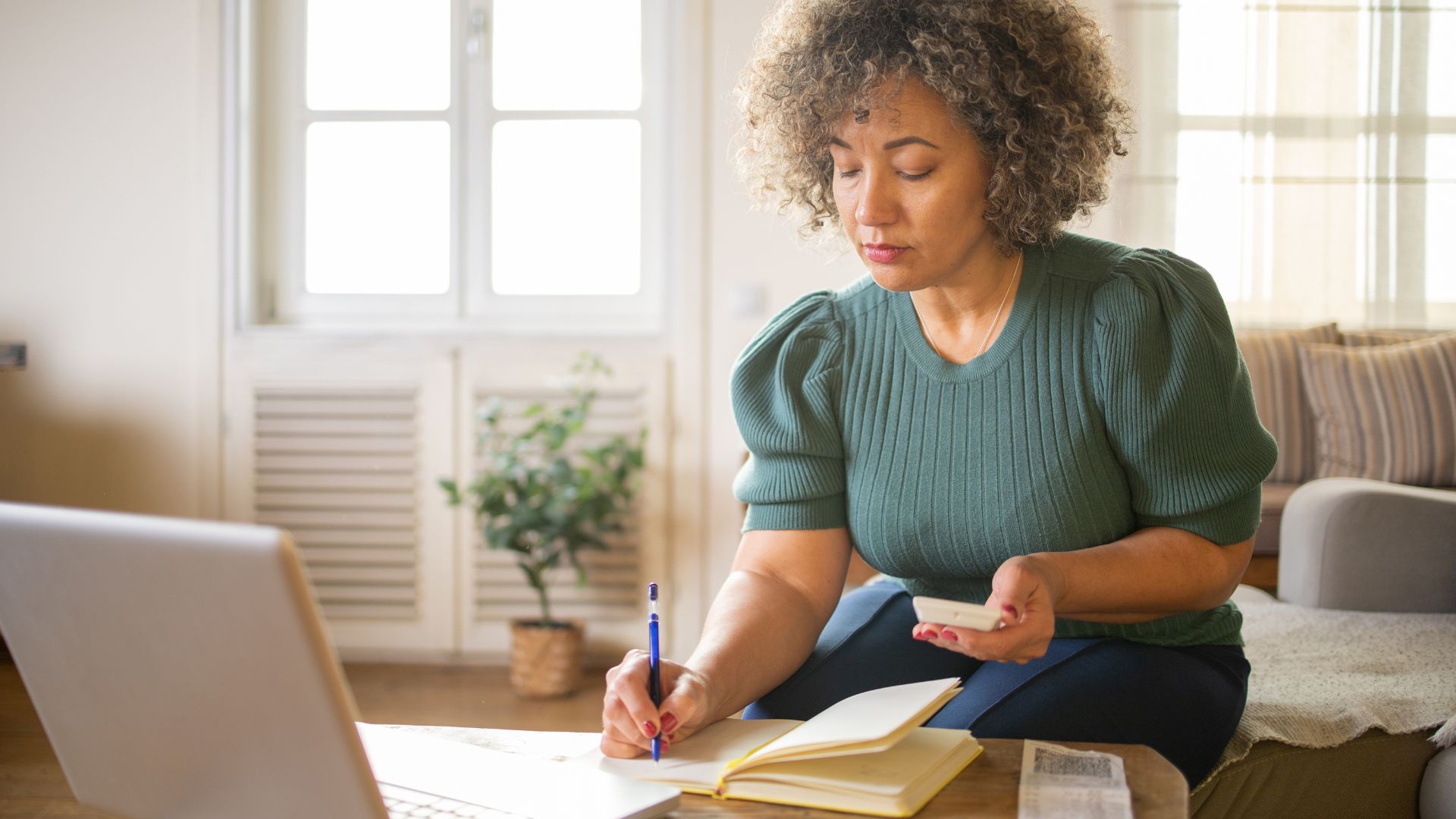 A woman sits in front of her computer while doing her taxes.