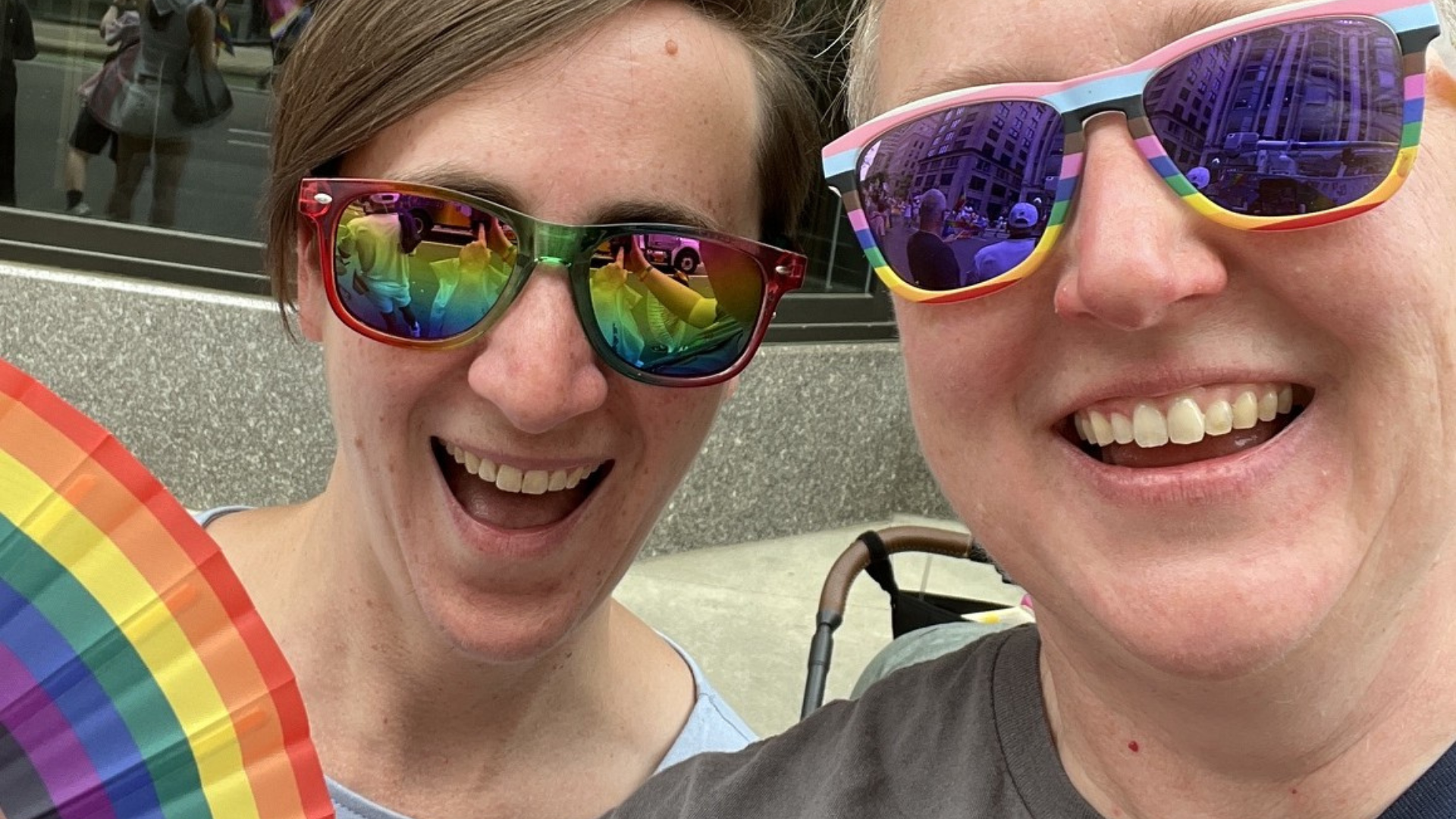 Two women smiling while attending a Pride event.
