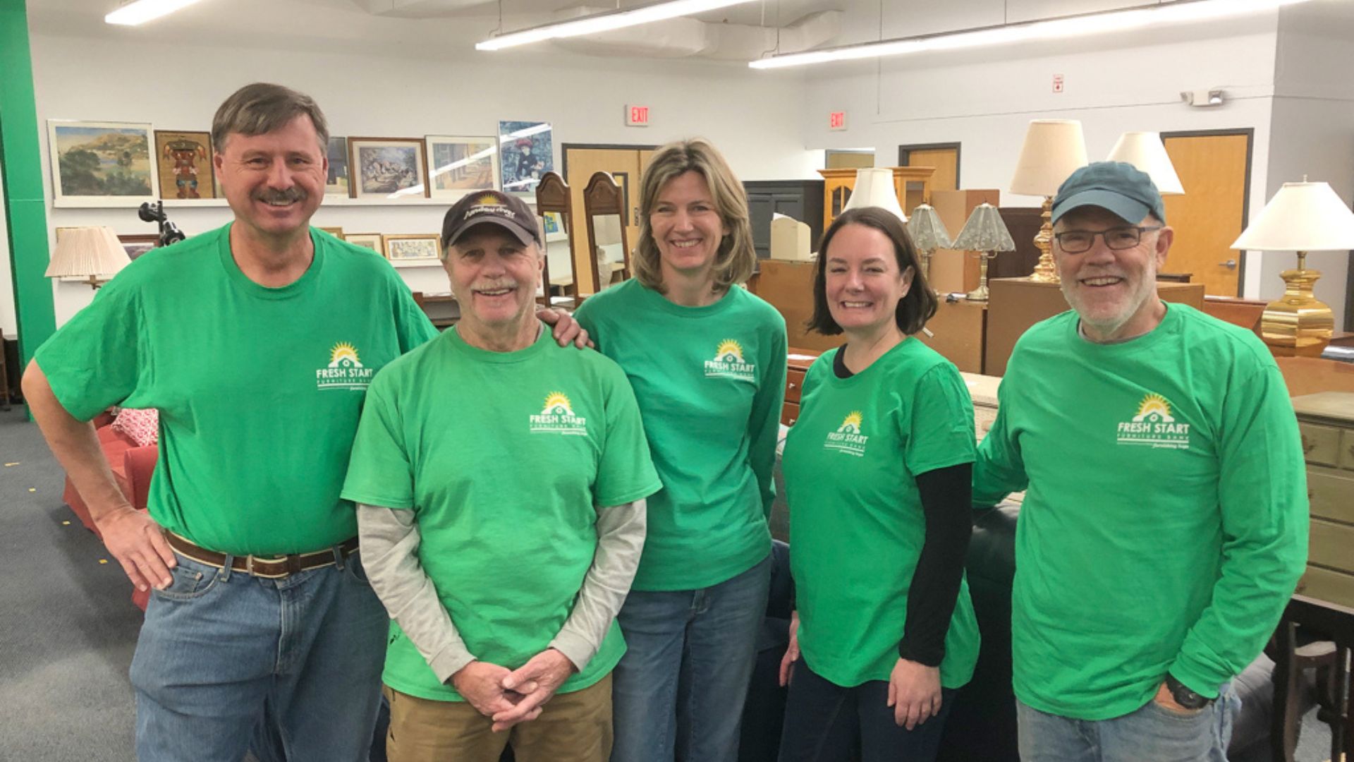 A group of volunteers in green shirts smiling.