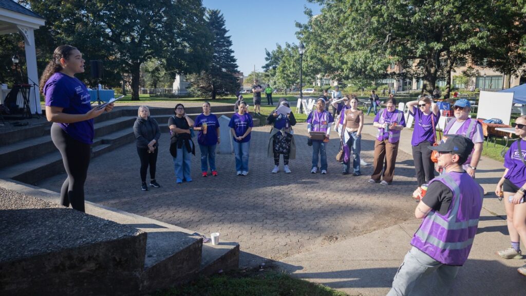 A group of people in purple shirts gathering in an outdoor space.