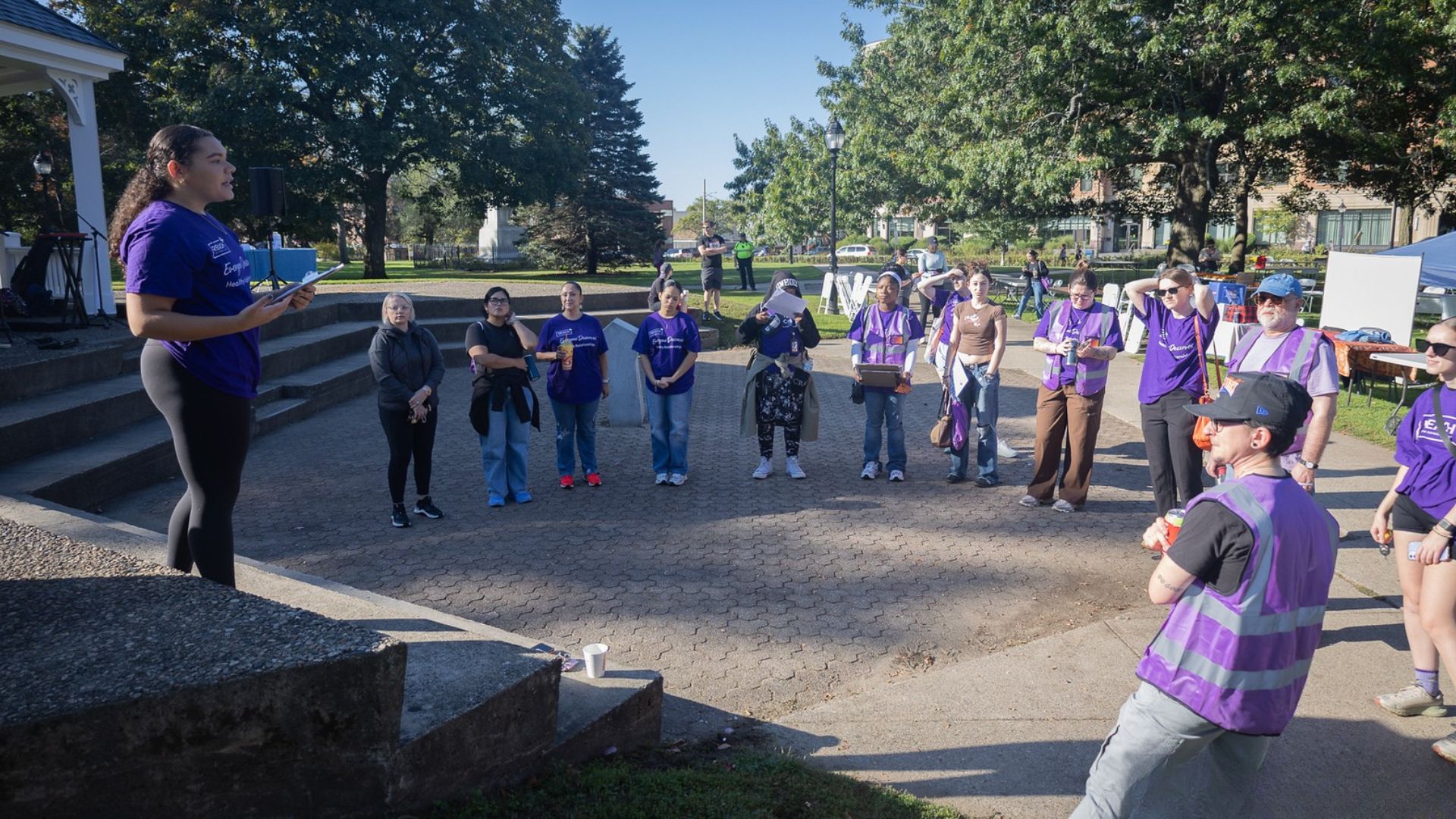 A group of people in purple shirts gathering in an outdoor space.