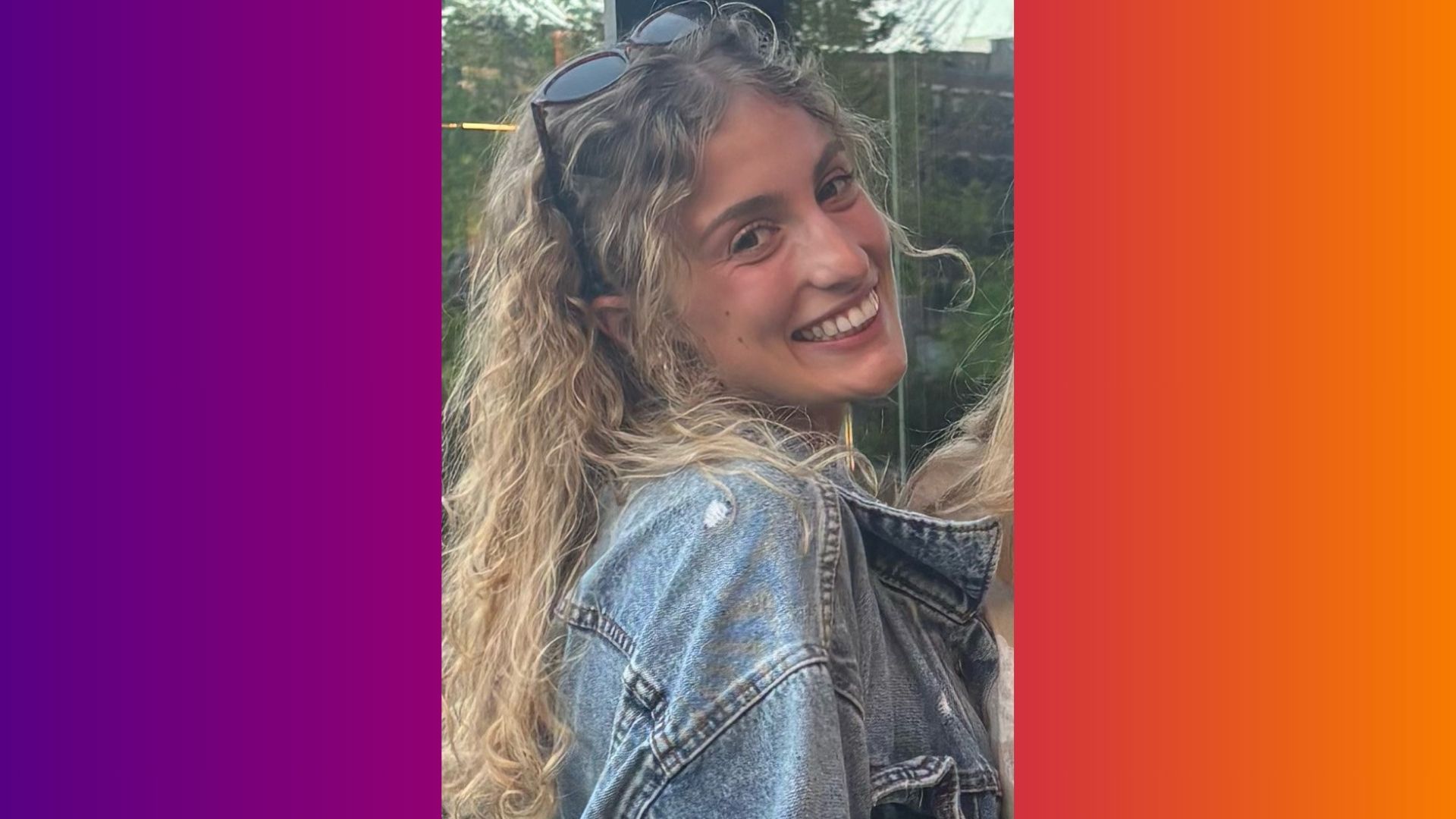 A young woman smiles while looking over her shoulder.